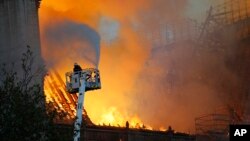 A firefighter uses a hose as Notre Dame cathedral is burning in Paris, April 15, 2019.