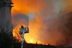 A firefighter uses a hose as Notre-Dame cathedral is burning in Paris, April 15, 2019.