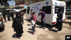 Un membre d'une ONG prend la température d'enfants dans le cadre de la lutte contre le coronavirus à Kafr Takharim, dans la province d'Idleb, en Syrie.
