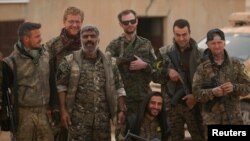 Syrian Democratic Forces (SDF) fighters pose with foreign volunteer fighters inside Tabqa military airport after taking control of it from Islamic State fighters, west of Raqqa city, Syria April 9, 2017. 