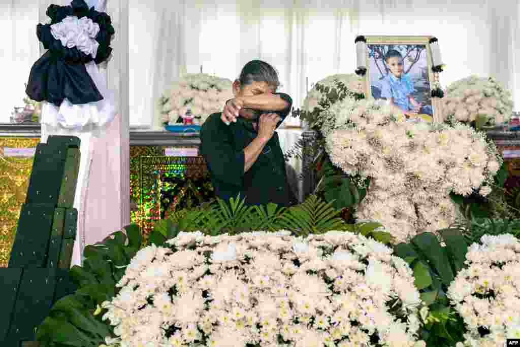 A relative cries in front of the portrait and coffin of a victim of a school bus fire at Wat Khao Phraya Sangkharam School in Uthai Thani, Thailand.&nbsp;Grieving families offered prayers for 23 children and their teachers killed in a horrifying school bus fire as the government vowed a crackdown on unsafe vehicles.&nbsp;