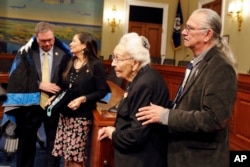 FILE - O.J. Semans, Sicangu Lakota, right, Miniconjou Lakota elder Marcella LeBeau, whose ancestor died at Wounded Knee, look on during a news conference June 25, 2019, in Washington. Then-members of Congress Paul Cook, left, and Deb Haaland are seen in the background.