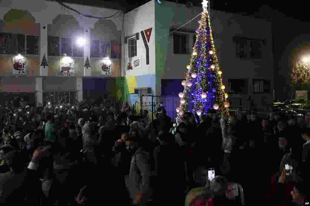 Cristãos palestinos reúnem-se para tirar fotos enquanto celebram a iluminação da árvore de Natal no pátio do centro cristão da juventude na cidade de Gaza. 10 Dezembro 2021