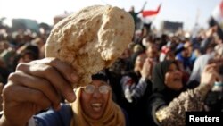 FILE - An Egyptian holds a piece of bread to protest against the high prices of goods in Tahrir Square in Cairo, February 8, 2013. 