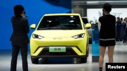 People use their phones in front of the BYD Seagull that is displayed at the Auto Shanghai show, in Shanghai, China April 19, 2023.