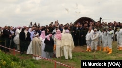 Yazidi priests release doves into the air after blessing a mass grave while the exhumation team stands by to begin their work in Kocho, Iraq, March 15, 2019. 