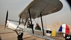 FILE - A vintage airplane lands during a rally across Africa, at the Giza Pyramids in Egypt, Nov. 13, 2016.