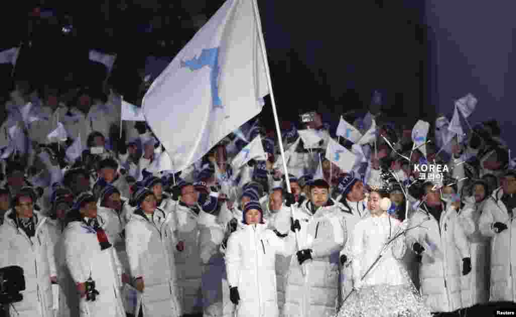 在平昌冬奥会开幕式上，朝韩两国代表手持半岛旗共同入场。照片拍摄于2018年2月9日。