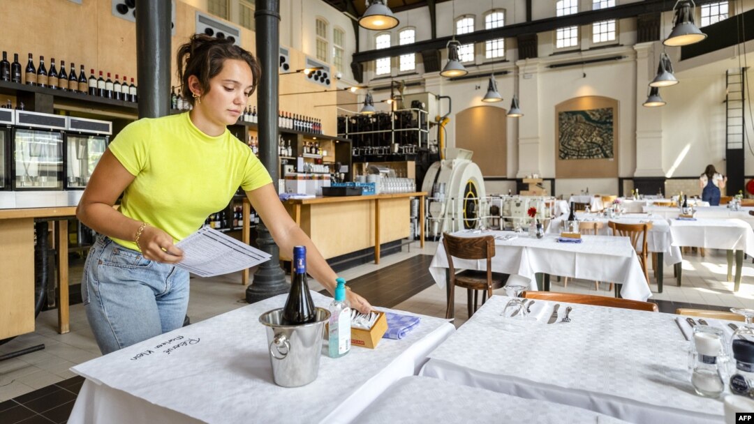 Seorang pekerja restoran menyiapkan meja-meja saat pembukaan kembali bisnis di Amsterdam, Belanda, Selasa (26/5). 