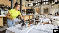 Seorang pekerja restoran menyiapkan meja-meja saat pembukaan kembali bisnis di Amsterdam, Belanda, Selasa (26/5). 