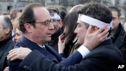 French President Francois Hollande comforts French columnist for Charlie Hebdo Patrick Pelloux as they take part with family members and relatives in a solidarity march in the streets of Paris, Jan. 11, 2015.