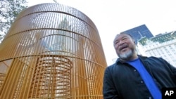 Chinese activist artist Ai Weiwei poses by one of his "Good Fences Make Good Neighbors" installations, "Gilded Cage," in New York's Central Park, Oct. 10, 2017. 