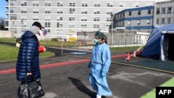 People are welcomed by a nurse at the pre-triage medical tent in front of the Cremona hospital, in Cremona, northern Italy, on March 4, 2020.