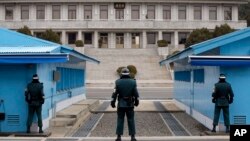 FILE - In this March 12, 2014 photo, a North Korean soldier, center top, looks at the southern side as three South Korean soldiers guard at the border village of Panmunjom, which has separated the two Koreas since the Korean War, in Paju, South Korea.