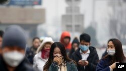 Warga Beijing berjalan dengan mengenakan masker untuk melindungi wajah dan penafasan mereka dari police saat berjalan kaki di kota tersebut, Selasa (8/12).