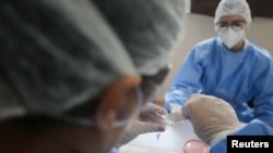 A health worker prepares a sample of test for the coronavirus disease (COVID-19), after cases of the Omicron variant were detected in Porto Alegre, Brazil, January 20, 2022. (REUTERS/Diego Vara)