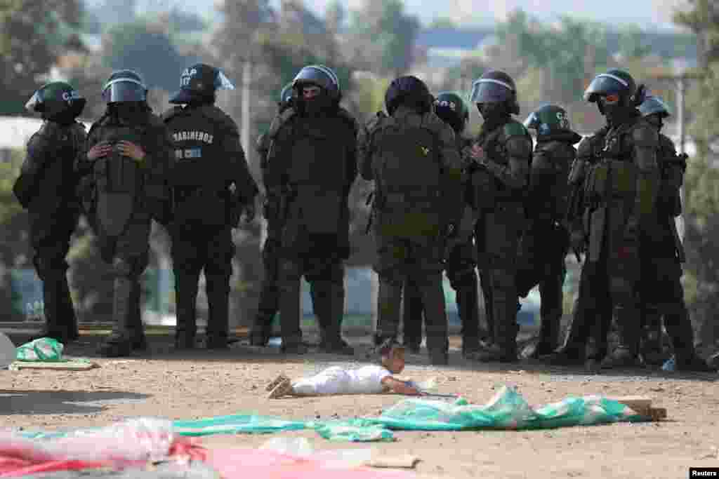 A child falls on the ground in front of riot police officers during an eviction of an unauthorized settlement without potable water, drainage system and electricity, where people have moved in with their families during the COVID-19 outbreak at Renca area on the outskirts of Santiago, Chile, March 10, 2021.