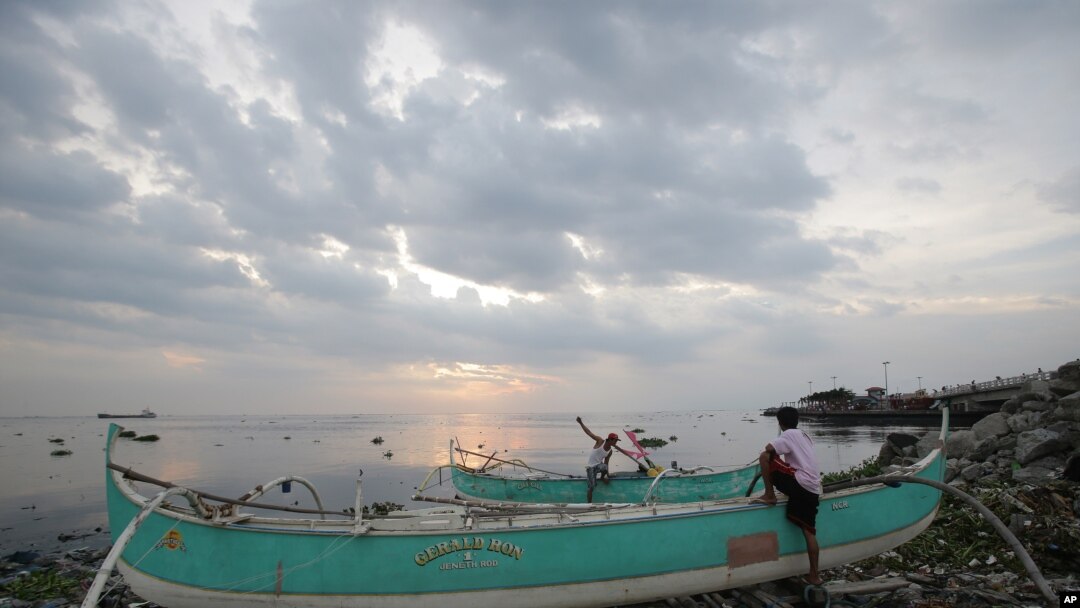 Nelayan Filipina tengah memeriksa perahu mereka yang mereka tambatkan di atas onggokan sampah di desa pantai Navotas, Manila Utara, Filipina (14/7). Warga Filipina tengah bersiap menghadapi badai tropis Rammasun, yang diperkirakan akan mencapai daratan di provinsi Catanduanes Selasa pagi (15/7).