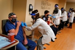 FILE - Staff members receive the COVID-19 vaccine at Holy Name Medical Center in Teaneck, N.J., Dec. 17, 2020.