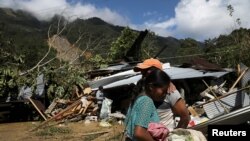 Gaspar Cal es abrazado por su hija Leticia mientras está parado frente a su casa, dañada por un deslizamiento de tierra causado por la tormenta Eta, mientras continúa la búsqueda de víctimas en el pueblo enterrado de Queja, el pasado 8 de noviembre.