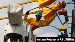 Seorang teknisi PLN mengenakan masker wajah saat memperbaiki jaringan listrik di tengah pandemi virus corona di Malang, Jawa Timur, 17 Juni 2020. (Foto: Antara Foto/Ari Bowo Sucipto via Reuters)