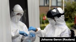 Staf medis menangani sampel di tempat pengujian drive-in untuk penyakit coronavirus (COVID-19) di sebuah rumah sakit di Brussel, Belgia 27 Juli 2020. (REUTERS / Johanna Geron)