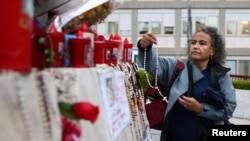 A woman places a rosary at the statue of late Pope John Paul II and Gemelli Hospital, where Pope Francis is admitted for ongoing pneumonia treatment, in Rome, Italy, March 12, 2025.