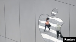 (资料照）2017年8月21日，一女子身影反射在美国加利福尼亚州旧金山市一苹果专卖店的标志中