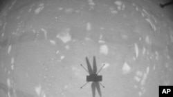 资料照片：NASA提供的图像显示，“机智号”直升机在火星第二次飞行时用黑白导航相机拍下自己的影子。(2021年4月22日)