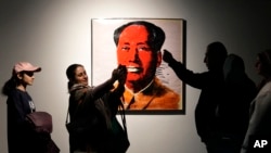 People take pictures next an Andy Warhol painting of China's late leader Mao Zedong at "Eye to Eye," an exhibit at the Tehran Museum of Contemporary Art in Iran, Nov. 21, 2024.