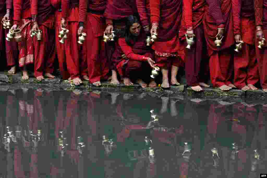 Nepalese Hindu devotees wait to fill pots with water from the Bagmati River at the Pashupatinath Temple during the month-long Swasthani festival in Kathmandu. Scores of married and unmarried women in the Himalayan nation are marking the month-long fast in the hope of a prosperous life and conjugal happiness.