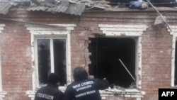 Esta fotografía tomada y publicada por la Oficina del Fiscal General de Ucrania el 6 de febrero de 2024 muestra a agentes del orden de pie junto a una casa dañada como resultado de un ataque con misiles en Zolochiv, región de Kharkiv, Ucrania.