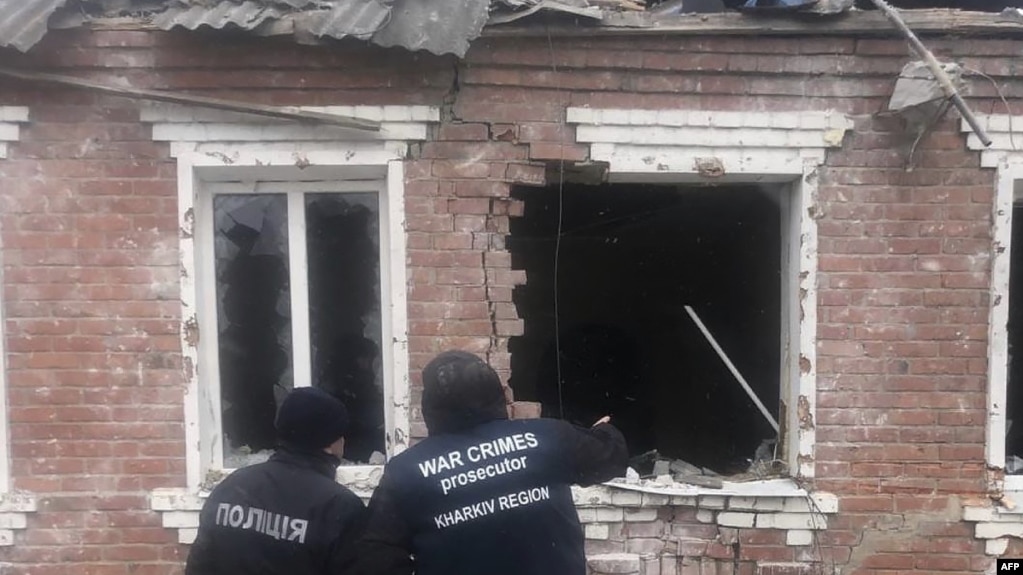 Ukrayna Başsavcılığı tarafından 6 Şubat 2024'te çekilip yayımlanan bu bildiri fotoğrafı, Kharkiv bölgesindeki Zolochiv'de füze saldırısı sonucu hasar gören bir evin yanında duran kolluk kuvvetlerini gösteriyor.