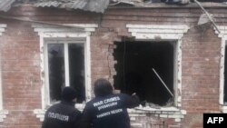 This handout photograph taken and released by the Office of the Prosecutor General of Ukraine on Feb. 6, 2024 shows law enforcement officers standing next to a house damaged as a result of a missile attack in Zolochiv, Kharkiv region.