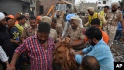 Rescuers carry the body of a victim at the site of an explosion at a fireworks factory in Batala, in the northern Indian state of Punjab, Sept. 4, 2019.