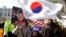 A supporter of impeached South Korean President Park Geun-hye waves flags of the U.S. and South Korea while another holds a portrait of the president during a rally in Seoul, South Korea, Feb. 27, 2017.