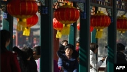 ARCHIVO - La gente descansa bajo linternas decorativas en la celebración del Año Nuevo Lunar del Dragón en Beijing el 13 de febrero de 2024. Un informe dice que los videos que promueven la cultura china son prominentes en los canales de YouTube en español de China.