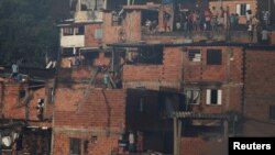 FILE - Residents pour water from their houses as they try to extinguish a fire at Paraisopolis slum in Sao Paulo, Brazil, March 1, 2017. 