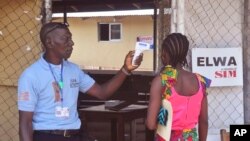 FILE - A unidentified family member, right, of a 10-year old boy that contracted Ebola, has her temperature measured by a health worker before entering the Ebola clinic were the child is being treated on the outskirts of Monrovia, Liberia, Nov. 20, 2015.