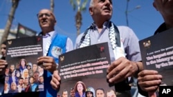 Palestinian journalists hold posters during a protest ahead of the one year anniversary of the Israel Hamas war, in the West Bank city of Ramallah, Oct. 6, 2024.