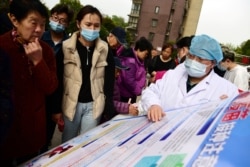 FILE - A community health worker disseminates information about vaccination against COVID-19 at a residential compound in Zhenjiang, Jiangsu province, China, Apr. 7, 2021. (China Daily via Reuters)