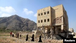 FILE - People walk past a school damaged during the ongoing war in Taiz, Yemen, Dec. 18, 2018. 