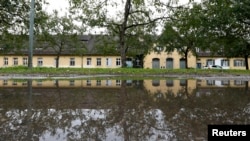 An annex of the former Nazi concentration camp Dachau, which has been turned into a shelter for homeless, including refugees, is reflected in a puddle in Dachau, Germany, Sept. 23, 2015.