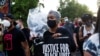 People raise their fists and hold signs and a banner as they march during an event in remembrance of George Floyd in Minneapolis, Minnesota, on May 23, 2021. 