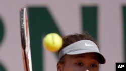 FILE - Japan's Naomi Osaka returns the ball to Romania's Patricia Maria Tig during their first round match of the French open tennis tournament at the Roland Garros stadium May 30, 2021, in Paris.