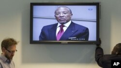 Journalists take notes as they listen to the verdict of the trial against former Liberian President Charles Taylor, seen on the screen in the court room of the Special Court for Sierra Leone in Leidschendam, near The Hague, Netherlands, April 26, 2012.