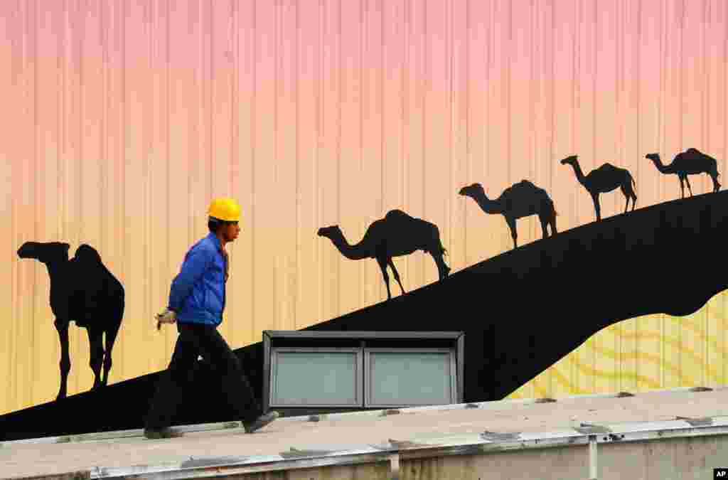 A laborer walks in front a poster at the construction site of the Africa pavilion at the 2010 World Expo site in Shanghai. (Reuters/China Daily)