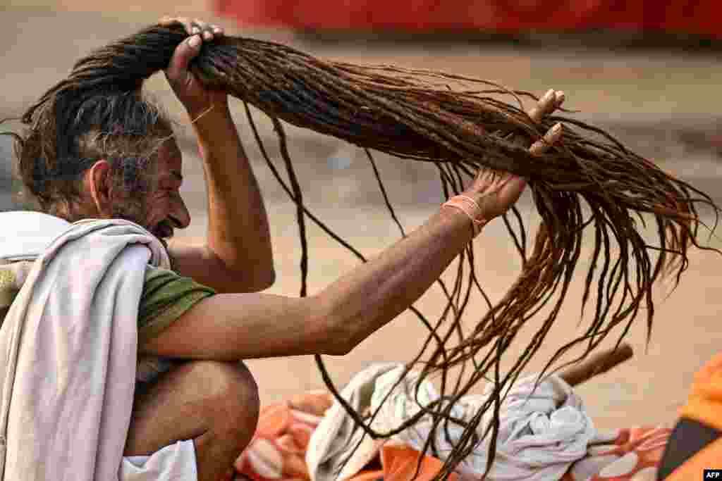 A Hindu holy man braids his hair as he leaves after taking a holy dip in the sacred waters of the Sangam, the confluence of Ganges, Yamuna and mythical Saraswati rivers, during the Maha Kumbh Mela festival in Prayagraj.