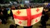 Seorang pengunjuk rasa memegang bendera Georgia selama protes oposisi terhadap hasil pemilu parlemen di Tbilisi, Georgia, Senin, 28 Oktober 2024. (Foto: AP/Shakh Aivazov)