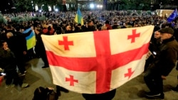 Seorang pengunjuk rasa memegang bendera Georgia selama protes oposisi terhadap hasil pemilu parlemen di Tbilisi, Georgia, Senin, 28 Oktober 2024. (Foto: AP/Shakh Aivazov)